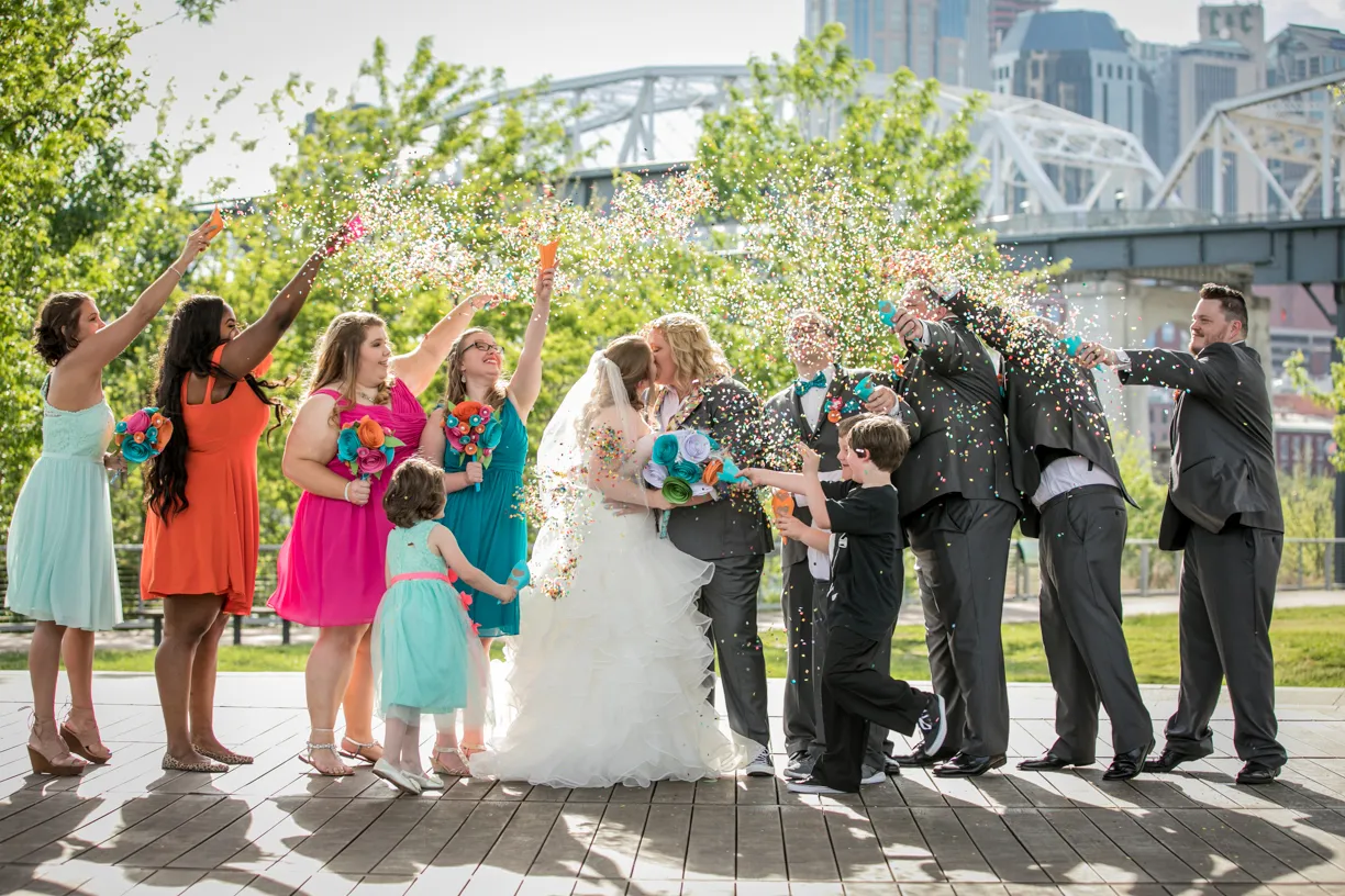 Wedding party throwing confetti on a riverside boardwalk