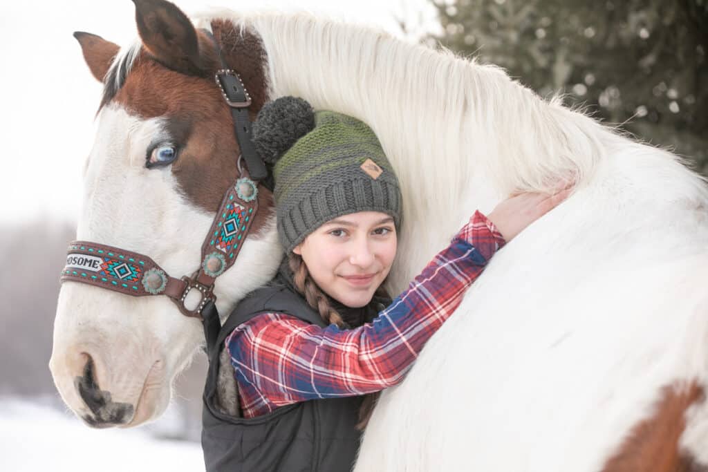 a girl hugging her horse