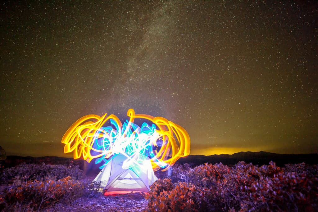light painting above tent with milky way