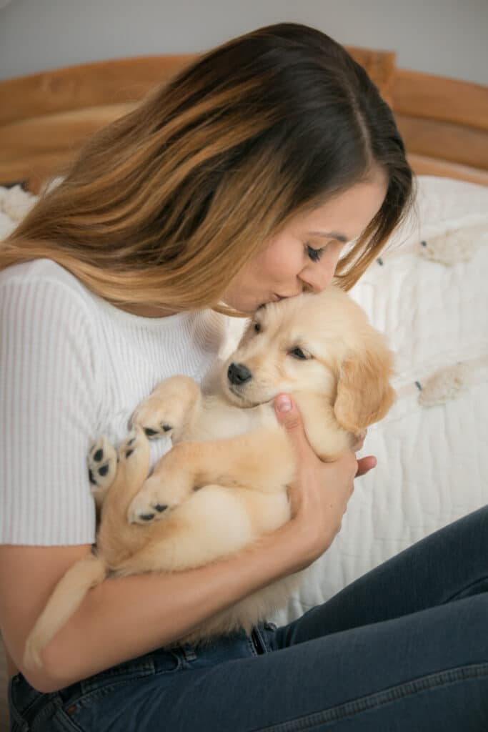 woman kissing puppy head