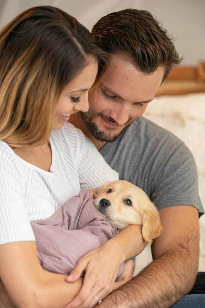 couple holding puppy like a newborn baby